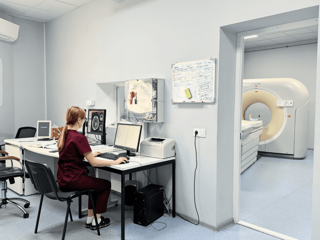 Лікар сидить за комп'ютером та перевіряє роботу МРТ-апарата