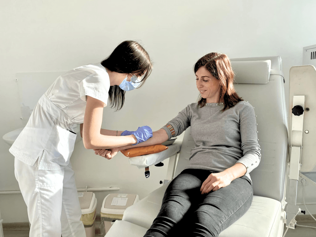 Лікар бере аналіз крові у жінки в медичному кріслі